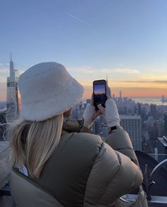 a woman taking a photo with her cell phone in new york city's skyline