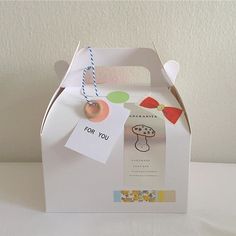 a white box with some tags attached to it and a string hanging from the top