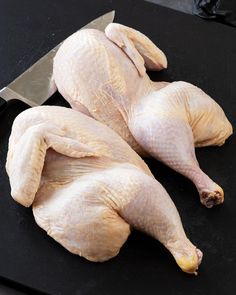 two raw chickens sitting on a cutting board with a knife next to them, ready to be cooked