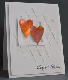 two heart shaped earrings on top of a white card with congratulations written in the middle