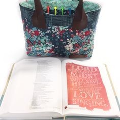 an open book sitting on top of a table next to a purse and pen holder