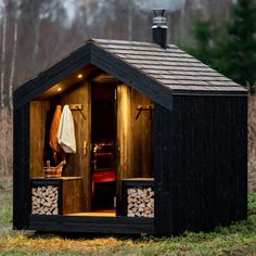 a small wooden cabin with logs in the door and windows on each side is lit up at night