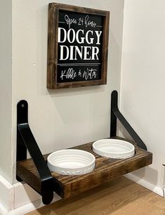 two bowls are sitting on a wooden shelf in front of a sign that says doggy diner