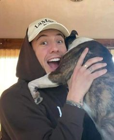 a woman holding a dog in her arms and wearing a hoodie on top of her head