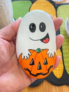 a hand holding an easter egg decorated with a ghost and jack - o'- lantern