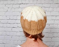 a woman wearing a white and brown knitted hat on top of a brick wall