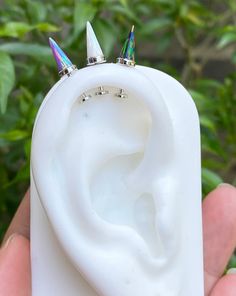 a person holding a fake ear shaped like a ring with two unicorn horns on it