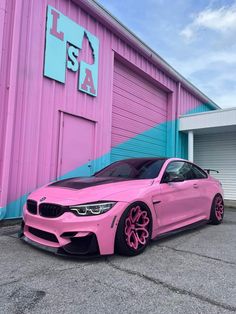 a pink car parked in front of a building with blue and pink paint on it