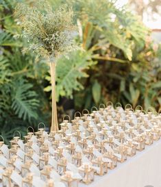 the table is set up with small gold vases and tiny white tags on them