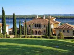 a large house with lots of trees and water in the background