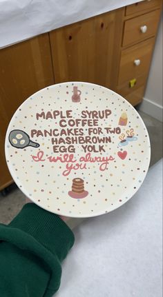 a person holding up a plate that says maple syrup pancakes for two have been made