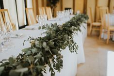 the table is set up with white linens and greenery on each place setting