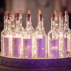 wine bottles are lined up on a barrel with lights in the top and below them