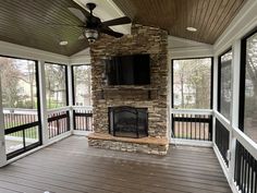 a large screened porch with a fireplace and flat screen tv