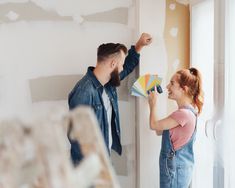 a man and woman are painting the walls together