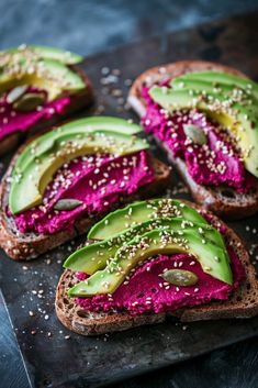 there is a sandwich with avocado and red beets on the side, along with sesame seeds