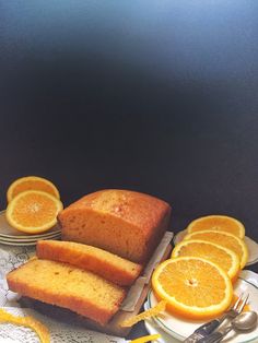 slices of orange pound cake on plates next to sliced oranges and silverware with forks