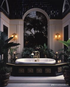 a bath tub sitting in the middle of a room with potted plants on either side