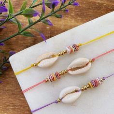 three seashells are sitting on a table next to some purple and yellow flowers