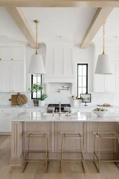 a large kitchen with white cabinets and wooden beams on the ceiling, along with two stools