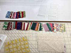 several pieces of fabric laid out on a cutting board next to scissors and rulers