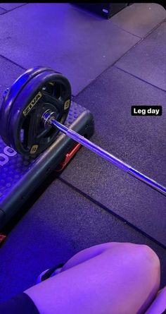 a woman's legs are on the ground with a barbell in front of her