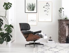 an eames chair and ottoman in front of three framed pictures