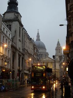 a double decker bus driving down a street next to tall buildings with domes on top