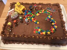 a birthday cake with the number 5 on it and various toys around it, all in chocolate frosting