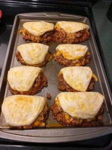 there are six sandwiches on the pan ready to be cooked in the oven and put into the oven