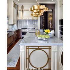 an image of a kitchen with marble counter tops and gold accents on the island top