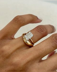 a woman's hand with a diamond ring on top of her finger and an engagement band