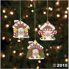 three gingerbread houses hanging from strings on a christmas tree