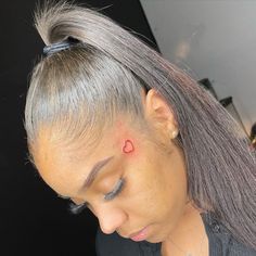 a woman with grey hair has a small red dot on her left side of the head