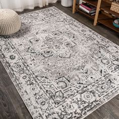 a large rug with an ornate design on the floor in front of a wooden table