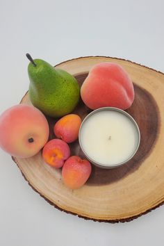 some fruit is sitting on top of a wooden plate with a candle in the middle