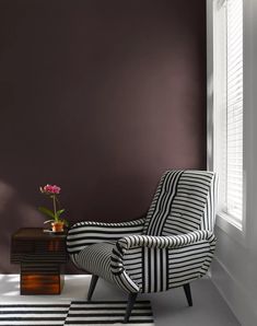 a black and white striped chair next to a table with a potted plant on it