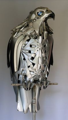 a metal sculpture of an eagle on a branch with eyes and wings cut out to look like it's from the side