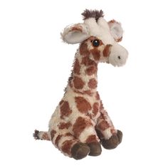 a stuffed giraffe sitting on the ground with its eyes open and tongue out