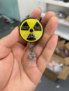 a hand holding a badge with the words not the nurse on it in black and yellow