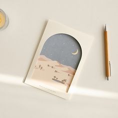 a card with a desert scene on it next to a pencil