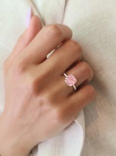 a woman's hand with a pink diamond ring on her left hand and a white background