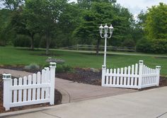 two white picket fenced in area with green grass and trees