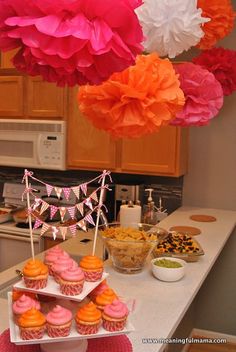 some cupcakes and other food on a table in a kitchen with hanging decorations