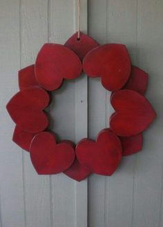 a red wooden heart shaped wreath hanging on a white door