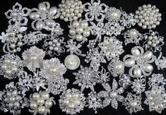 many different types of pearls and brooches on a black background with white flowers