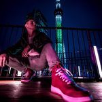 a man sitting on the ground in front of a building with a neon shoelace