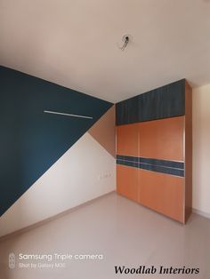 an empty room with wooden cabinets and blue accent on the wall, in front of a white ceiling