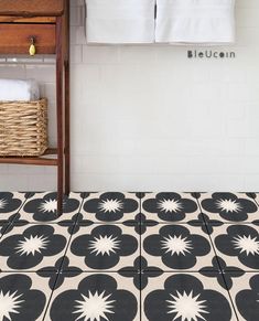 a bathroom with black and white tiles on the floor next to a towel rack holding towels