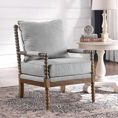 a gray chair sitting on top of a rug next to a table with a lamp